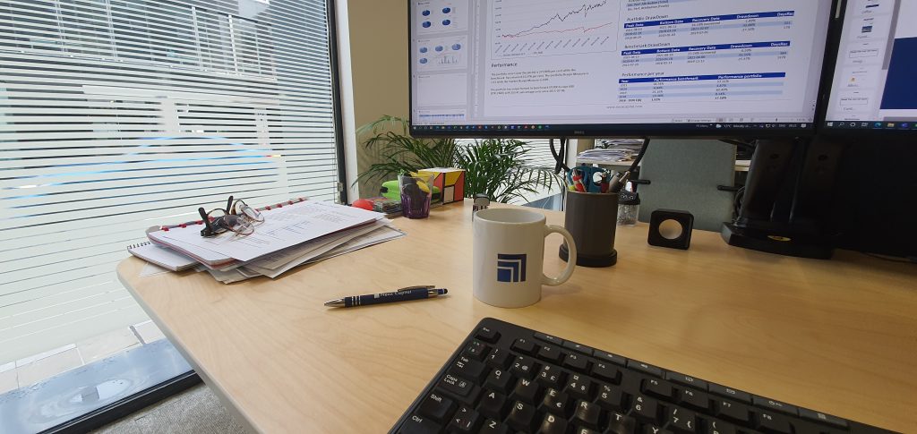 A wooden desk with computer on.