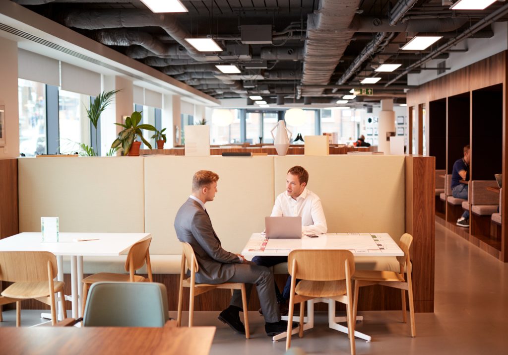 Two people in suits talking at an office.